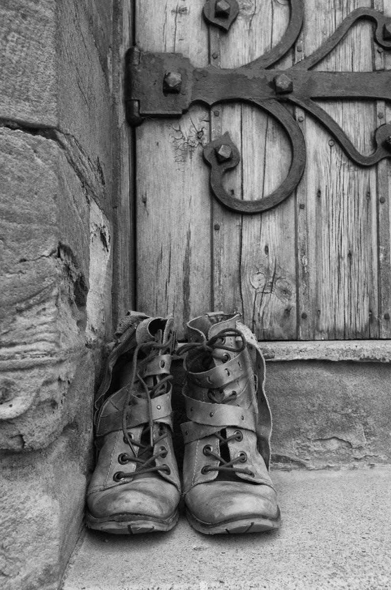 A Pair Of Worn Boots Outside A Door